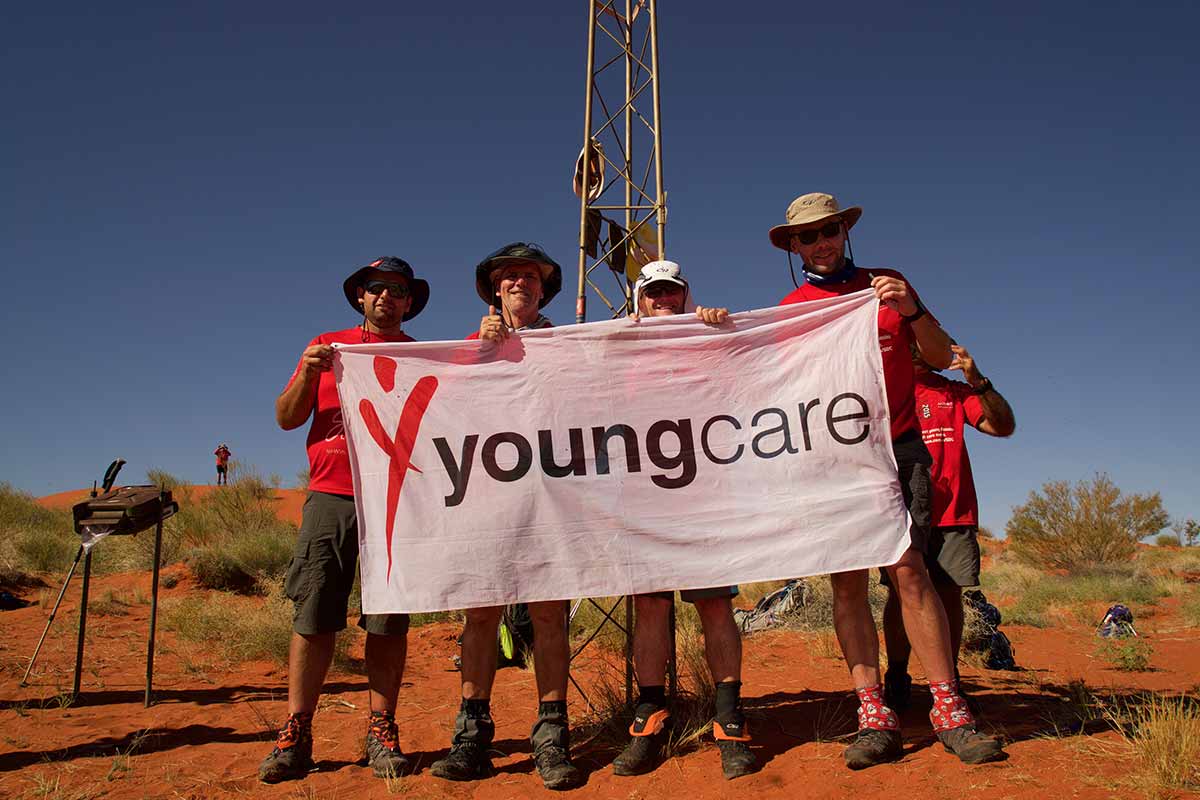 Four Suncorp trekkers at geo centre holding Youngcare flag